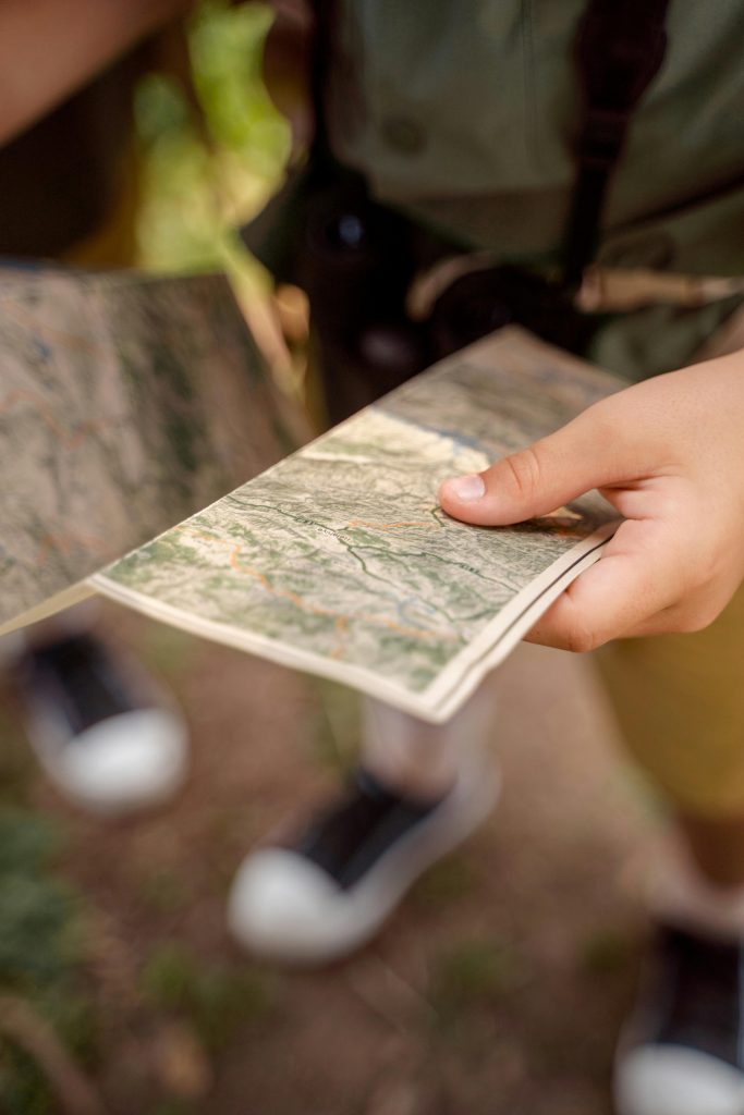 pexels photo 9292929 9292929 Close-up of a child holding a map outdoors, exploring in nature during a sunny day.