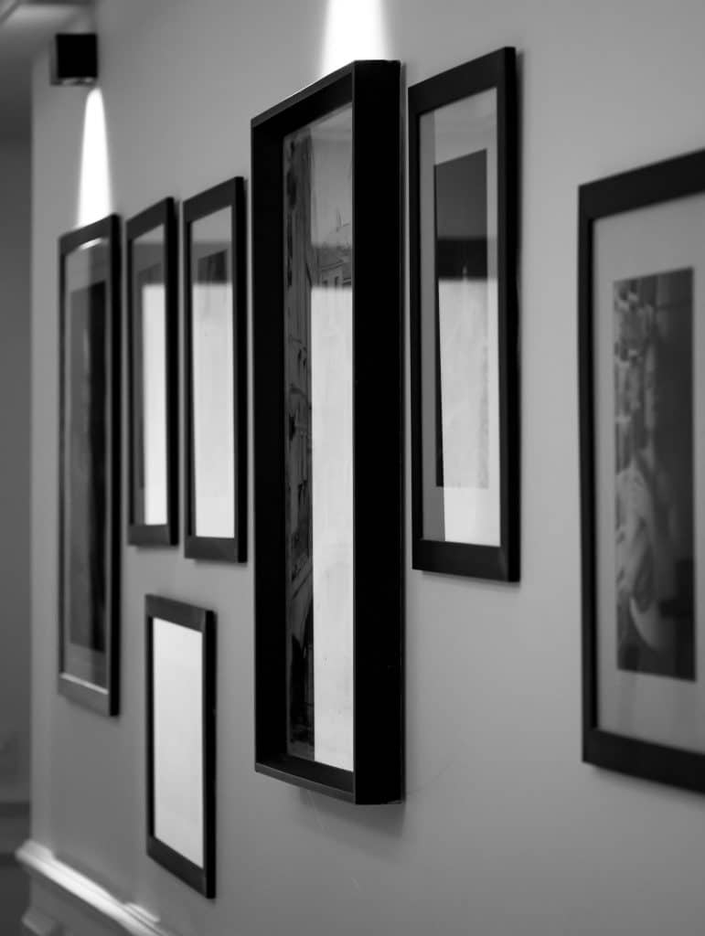 Monochrome wall display in an art gallery with framed pictures casting soft shadows.